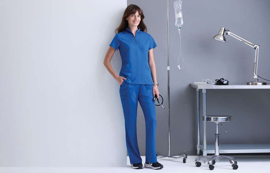 Healthcare worker in blue scrubs with medical equipment in a clinical setting